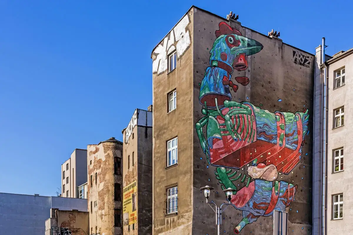 Kolorowy mural przedstawiający mechanicznego ptaka zdobi fasadę kamienicy.